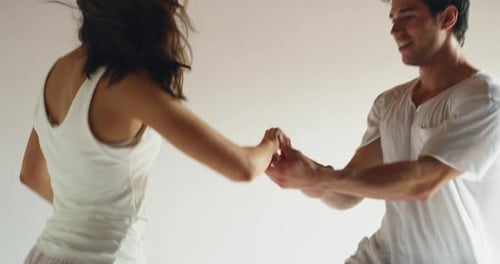 Slow motion close up of young just married couple wearing pajamas having fun to dance in the bedro