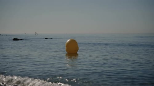 A Serene Scene of a Yellow Buoy Peacefully Floating on a Calm Sea Under a Clear Sky