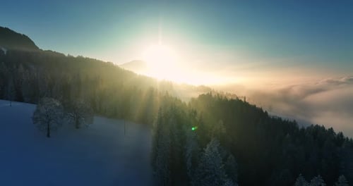 Ein friedlicher und heiterer Wintersonnenaufgang wirft einen wunderschönen Schein über die verschneiten Berge