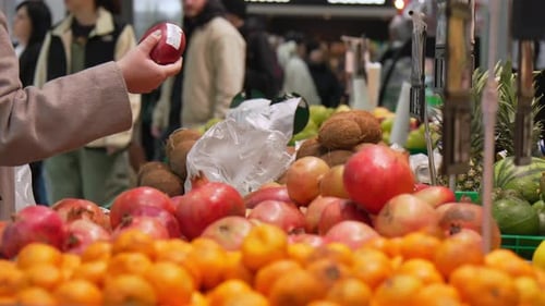 Unrecognizable girl choosing Maango in supermarket next to organic fruit shelf