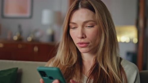 Worried Woman Looking at Smartphone Screen Indoors