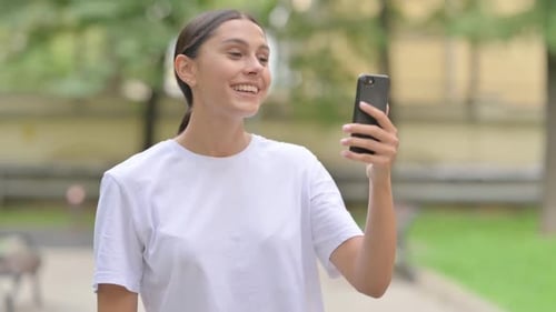 Woman Video Chats on Smartphone in Urban Park