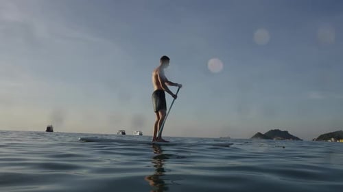 Western Man Paddling Atop His Paddle Surfboard on the Sea