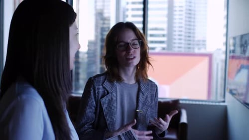 Creative Businesswomen With Proofs Watching Video In Office