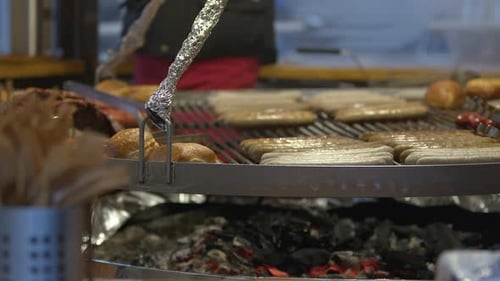 Sizzling Sausages and Buns Cooked over Coals