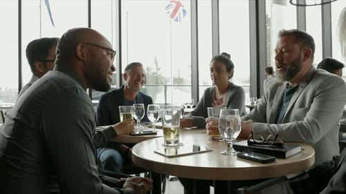 Business People Talking and Drinking Beer at Restaurant Table Bar
