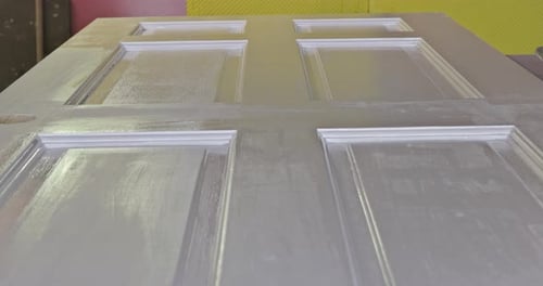 Applying White Paint with a Roller to the New Door Before Painting It