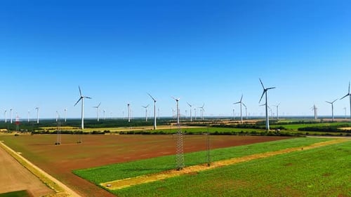 Windturbinen auf einer grünen Wiese. Hohe Windräder ragen über grüne Felder