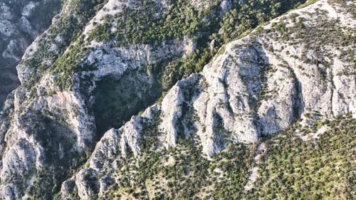 Aerial footage of a rock formation with trees on the mountain