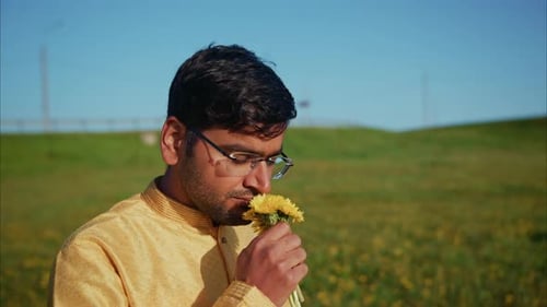 Young Indian Man Smelling Dandelions in a Field