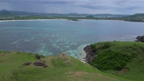 Aerial View of Man on Hill Overlooking Tropical Bay