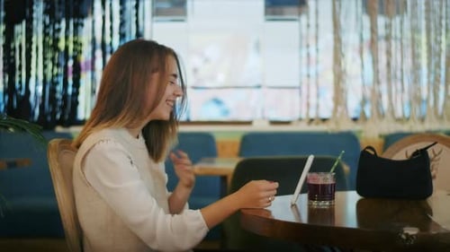 Joyful Girl Drinking Tea in a Cafe and Talking on the Phone or Video Call Happy Pastime