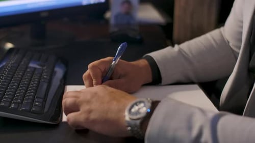 Person Writing on Notepad at Office Desk
