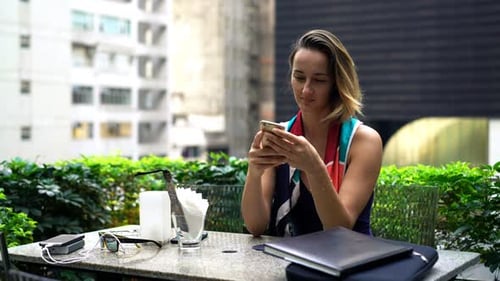 Young, Pretty Woman with Smartphone Sitting in Cafe Alone