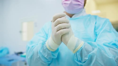 Hände des Chirurgen, Arztes in Uniform und sterilen Handschuhen, Nahaufnahme vor der Operation im Gesundheitskrankenhaus