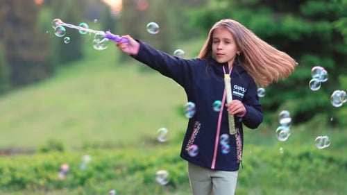 Girl in Black Jacket Walks in Forest and Blows Soap Bubbles