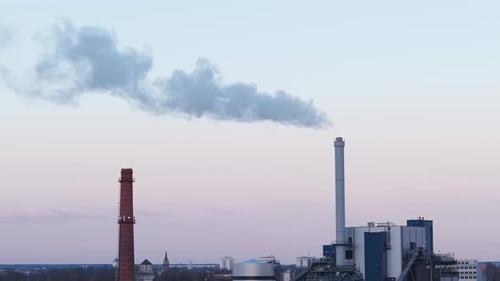 Industrial factory chimneys releasing smoke into the air, environmental impact visible