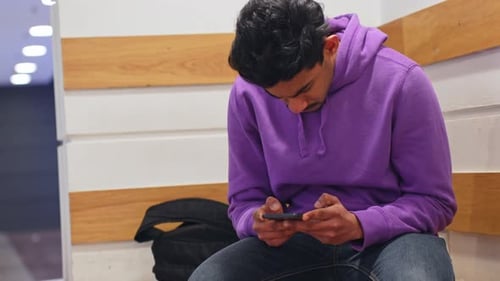 Young man hard focused on smartphone while sitting inside office