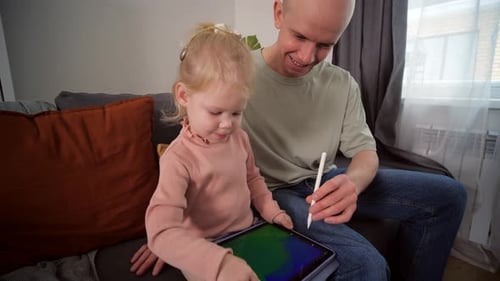 A Child with Cochlear Implants Plays with a Tablet Computer with His Father
