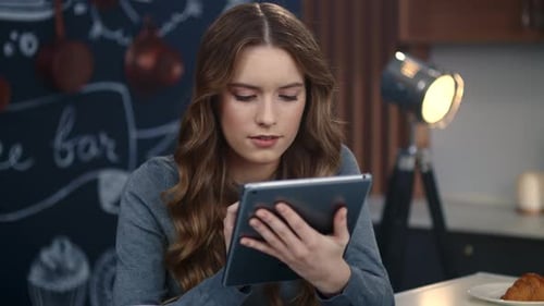 Woman using tablet in cafe with coffee and croissant