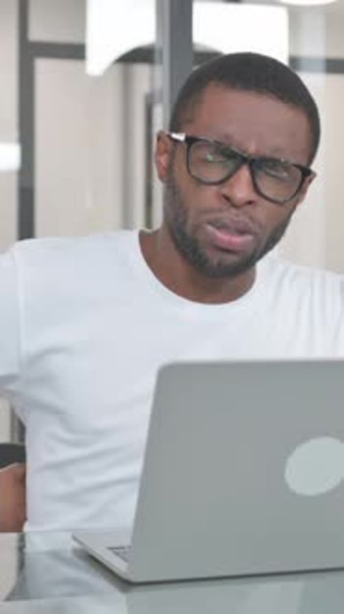 Young African Man Working on Laptop in Office, vertical video