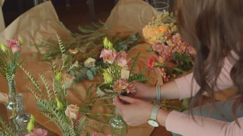 Woman with long brown hair decorating flower bouquets, back handheld view