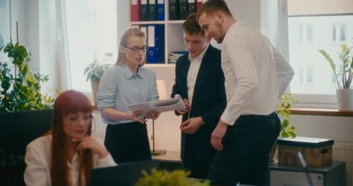 Businesswoman Explaining Coworkers Over Document in Office