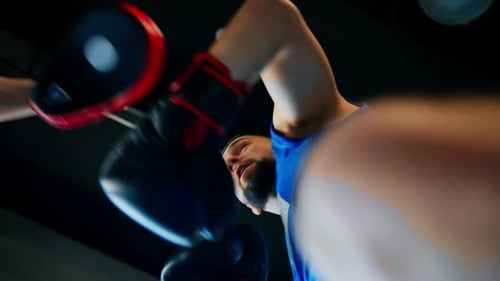 Sportsman in boxing gloves trains his boxing partner to practice punches close-up from below