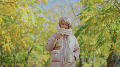 Woman Adjusting Scarf on Autumn Day