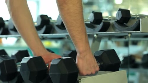 Closeup of a Young Man's Hands Gripping a Dumbbell in the Gym