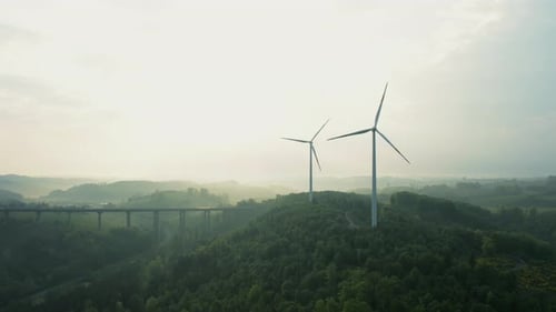 Drone View Over Wind Turbines and Bridge Under Grey Skies