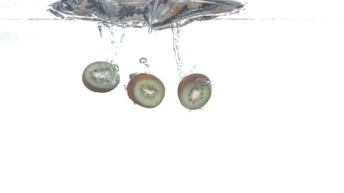 Three kiwi fruit slices fall into water