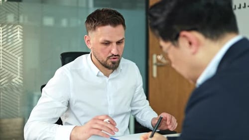 Businessmen Discussing Strategy and Data Analysis in a Modern Office Meeting