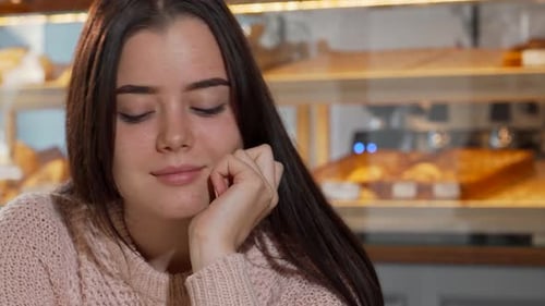 Young Woman Drinking Coffee in Bright Bakery