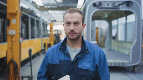 Professional Bearded Young Male Engineer Wearing Industrial Clothes Holding Tablet Computer Posing