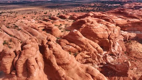 Aufnahmen über den sonnenbeschienenen roten, abgerundeten Felsen. Verlassene Landschaft mit Sträuchern im Hintergrund
.