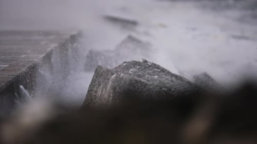 Shallow focus shot over breakwater as stormy winds blow sea spray and spume