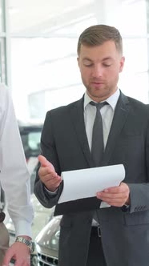 A Lovely Couple is Talking to a Manager While Buying a Car at a Car Dealership Vertical Video