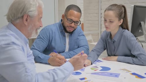 Business Team Analyzing Charts at Office Table