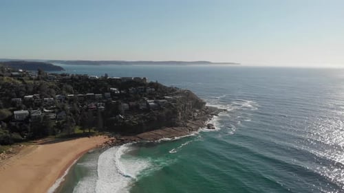 Luftaufnahme der Küste mit Sandstrand, blauem Wasser und felsiger Klippe