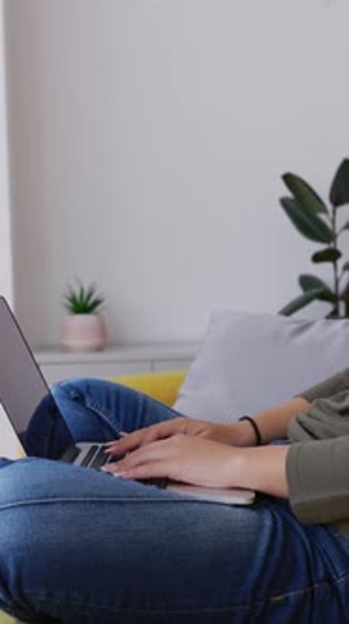 Young Adult Typing on Laptop While Sitting on Sofa