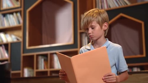 Boy Reads Book in Library Shelf Background
