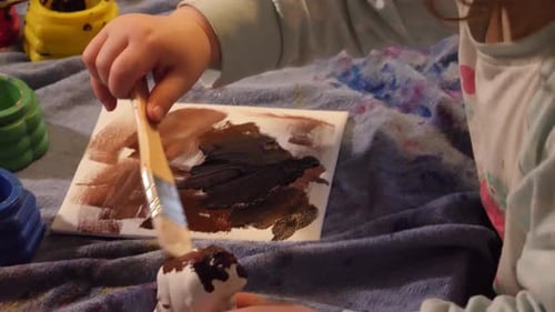 Young Child Painting a Figurine and Canvas