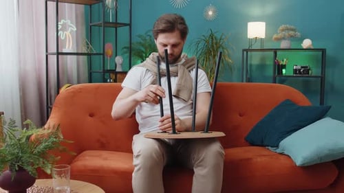Man Building Furniture on Orange Couch Indoors