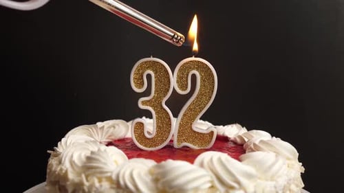 32. A candle in the form of the number 32, inserted into the holiday cake, is lit. Celebrating a bir