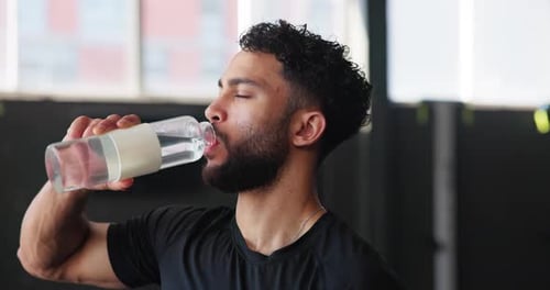 Man, thirsty and drinking water at gym, hydration and bottle of mineral liquid for nutrition