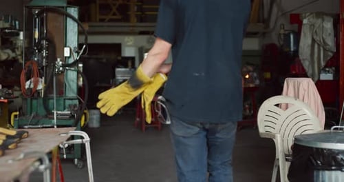 Professional blacksmith walks into his workshop looking for metal to work with