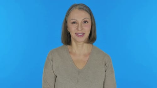 Vieille femme souriante sur fond bleu, portrait