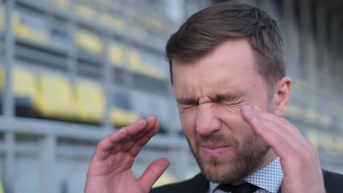 Man Massaging Temples in City