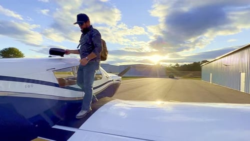 private pilot dismounts wing of piper cherokee 180 with sunset in background